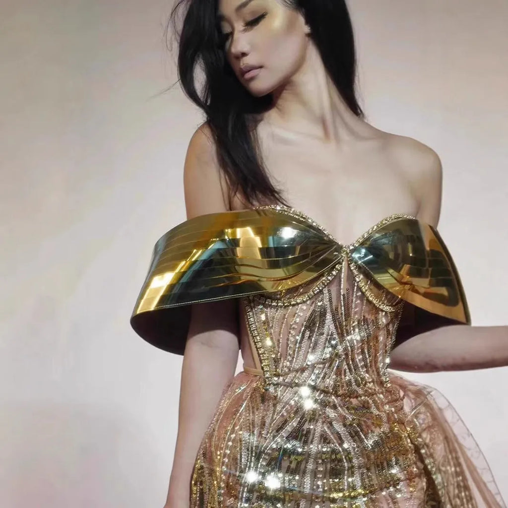 Gold strapless long dress with sequined tulle skirt and high side split, worn as formal evening wear.