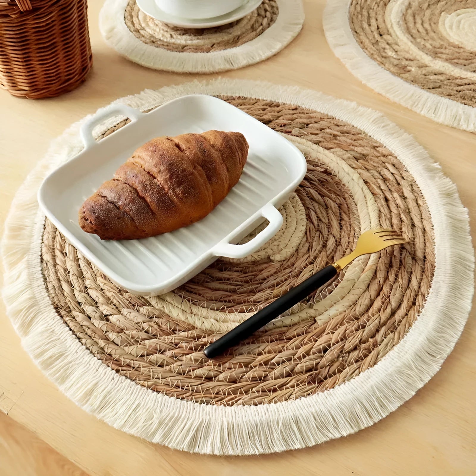 Round natural papyrus straw placemat with decorative tassels on a table