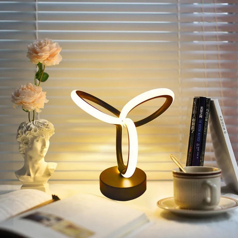 Black musical note shaped Bluetooth light with remote control on a bedside table.