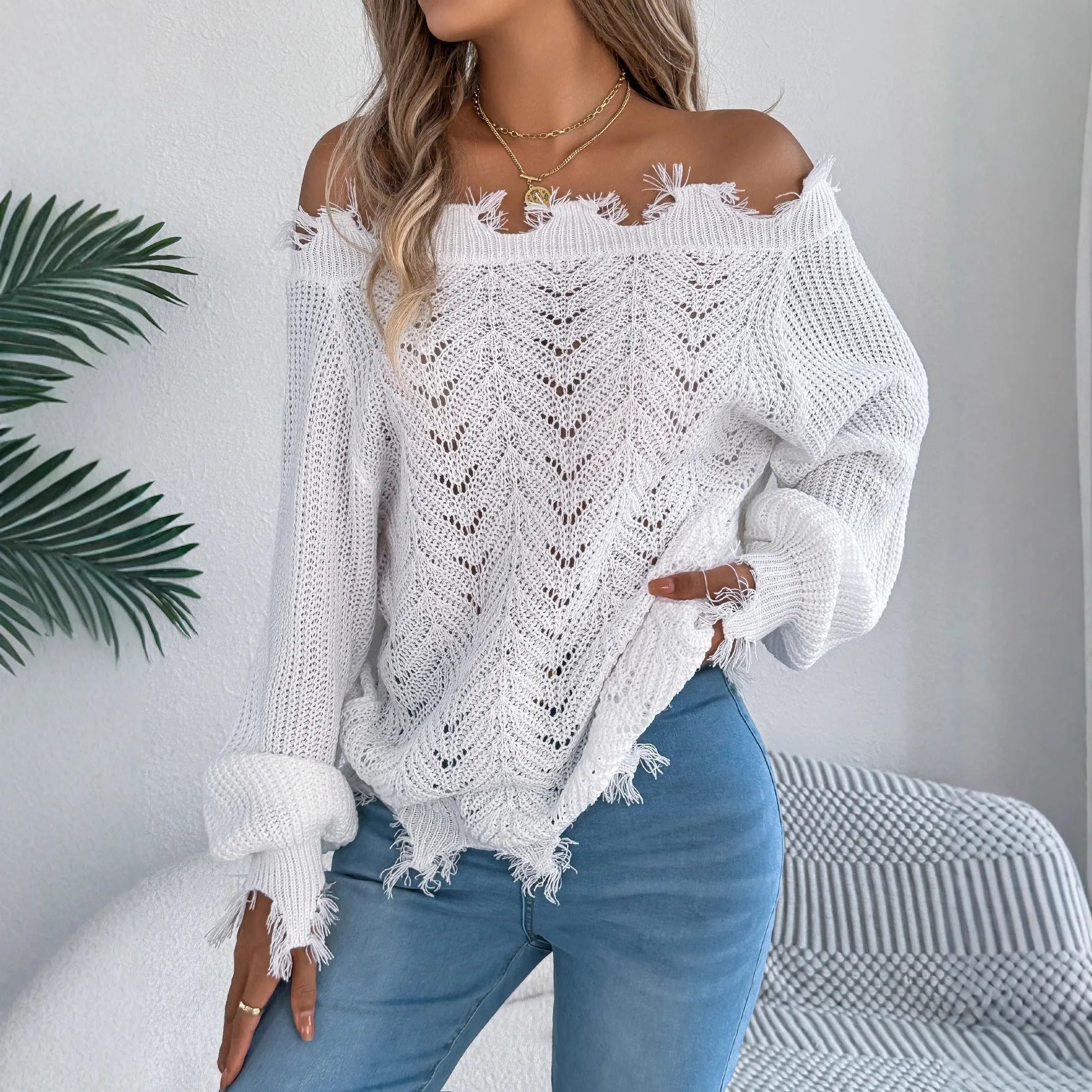 White women's hollow-out knit sweater with an off-the-shoulder neckline and long sleeves.