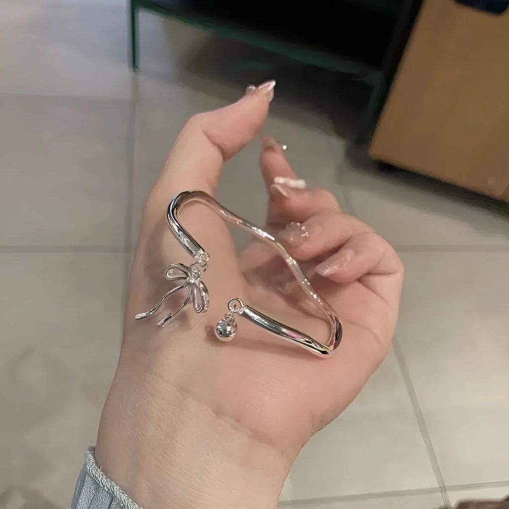 Silver bow charm adjustable bracelet with electroplated finish and bell opening mechanism