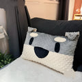 Grey schnauzer and white West Highland puppy decorative cushion pillow on a sofa.