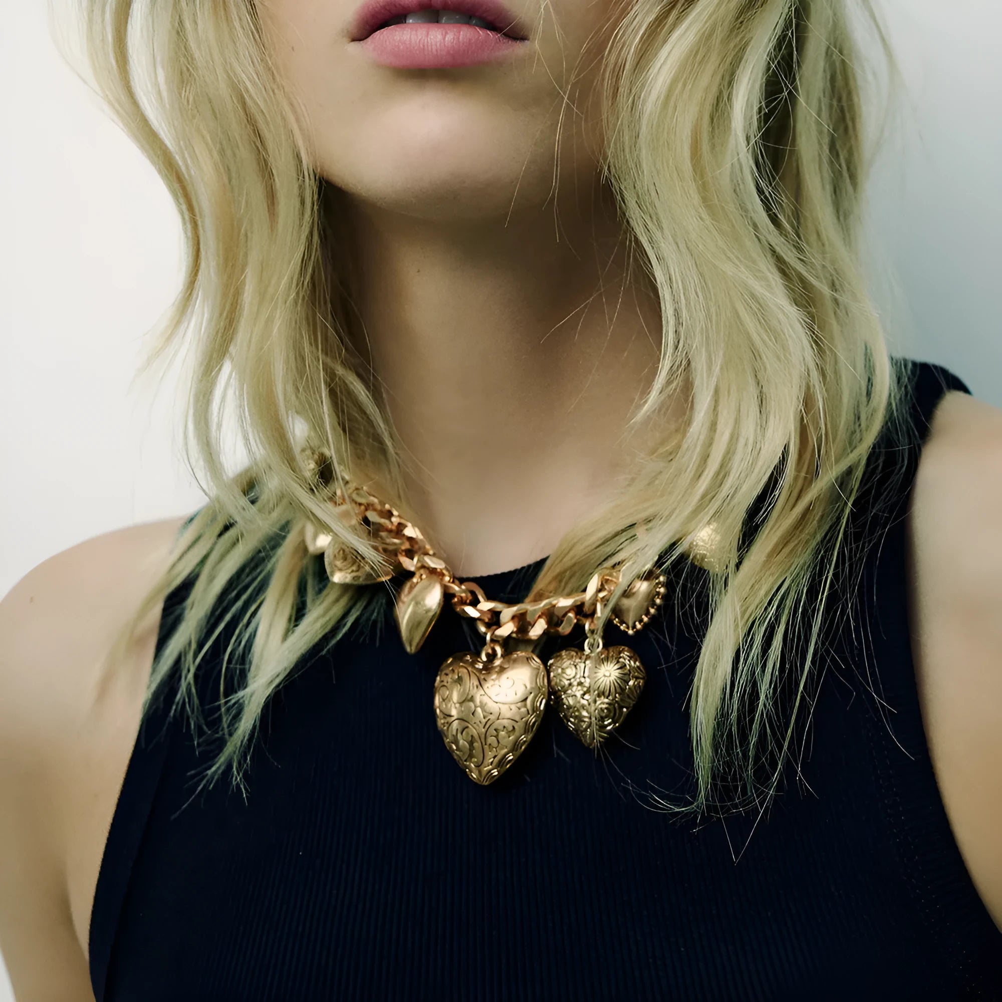 Gold carved heart pendant necklace with adjustable chain on white background
