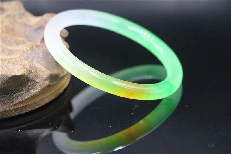 Jade bracelet with carved floating flower and auspicious cloud pattern in emerald green.