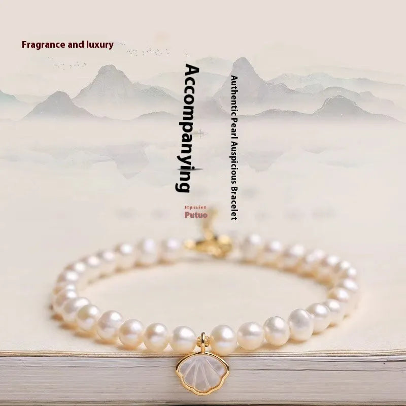 Women's freshwater pearl bracelet with a shell charm on a 16cm elastic string.
