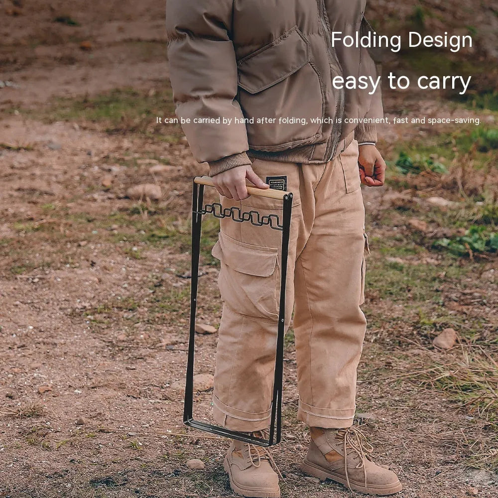 Black outdoor folding iron trash rack with a wooden handle, holding a bin bag.