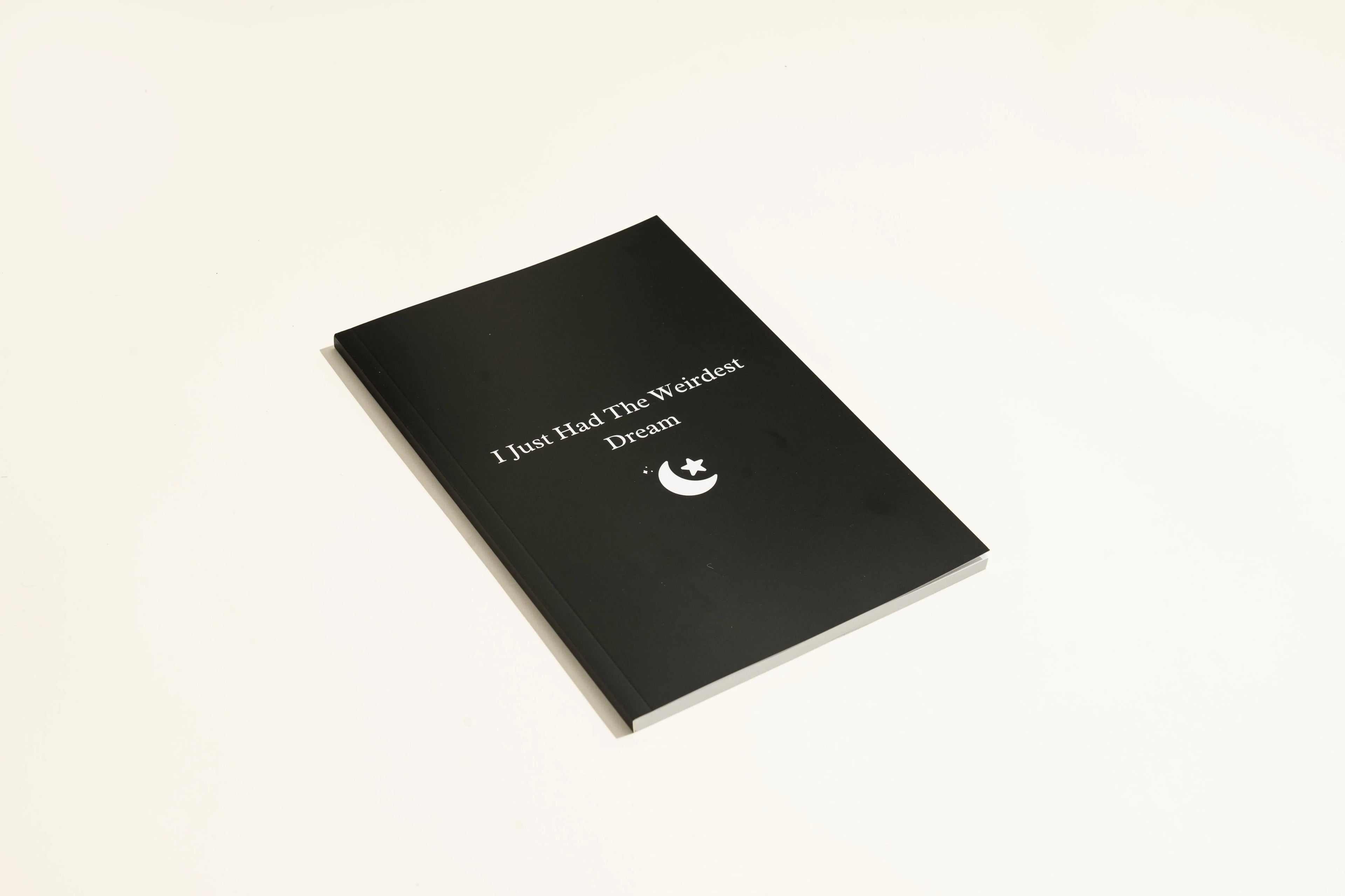 Black covered dream journal notebook open to show cream dot grid pages
