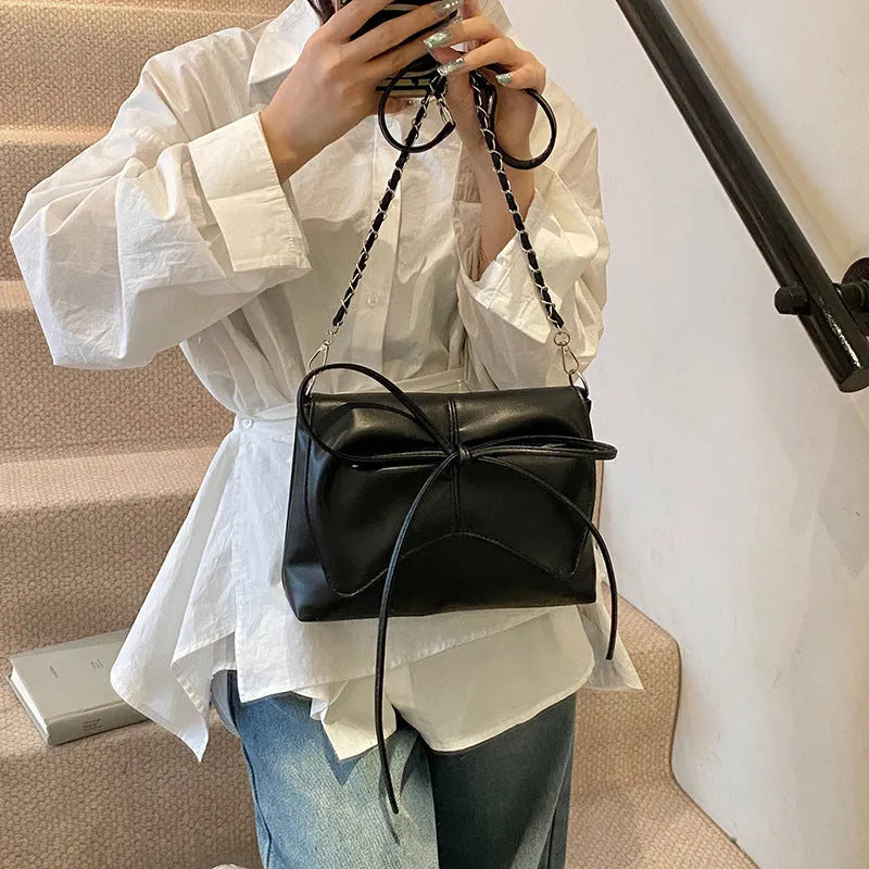 Women's black underarm bag in horizontal square shape showing sandwich pocket design and crossbody strap