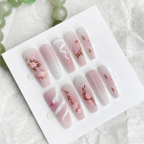 Ancient Chinese style snake year red prefabricated nail tips in drunk flower colour, long ladder shape, on a display stand