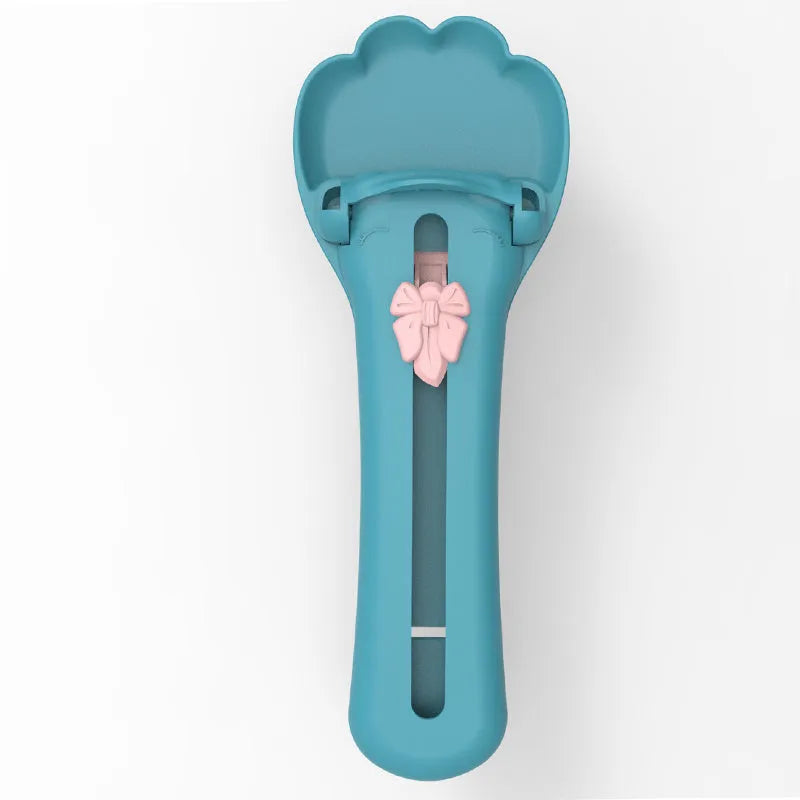 Green and pink pet food squeezer feeder with attached spoon for dispensing liquid and dry food