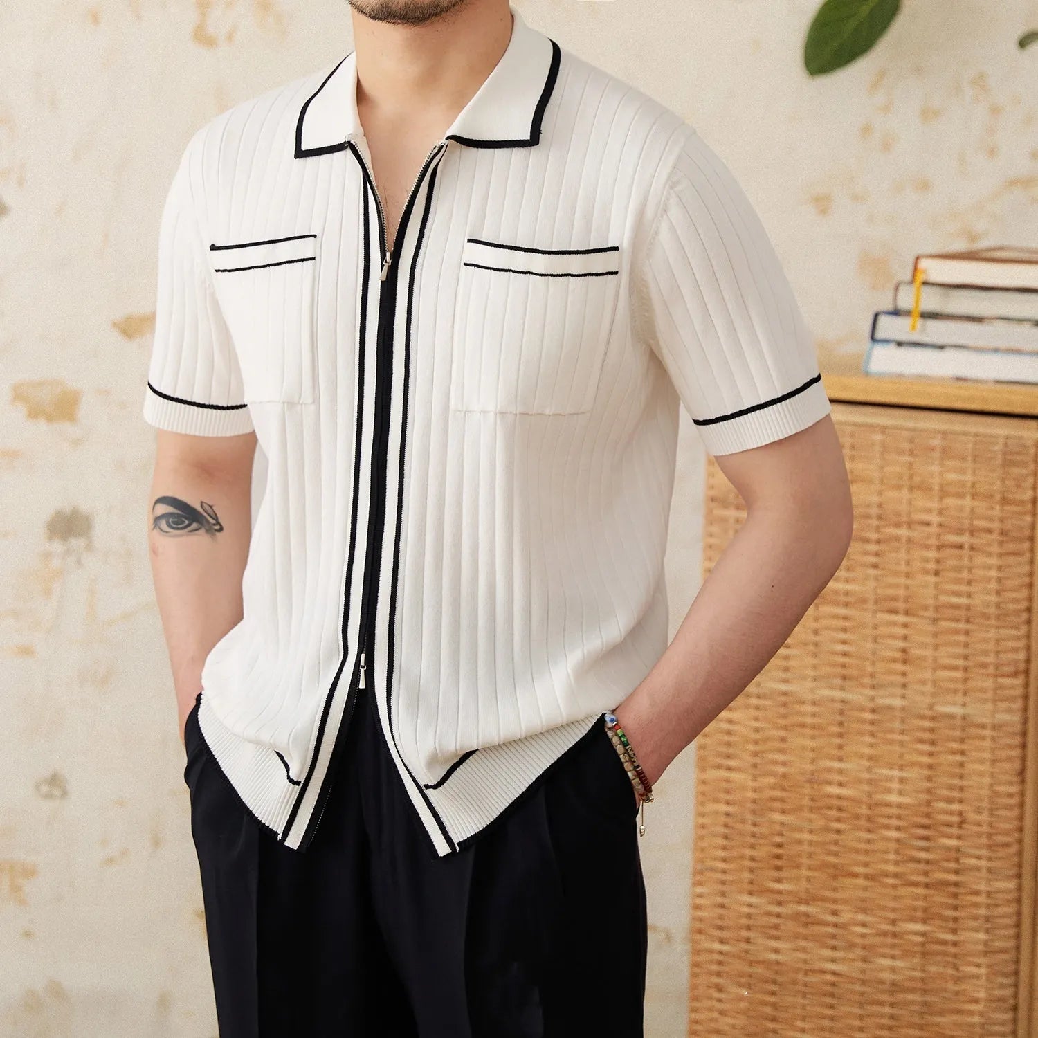 Man wearing a slim fit black knitted polo shirt with a lapel collar and short sleeves.
