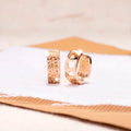 A pair of rose gold hollow heart-shaped earrings for women on a white background.