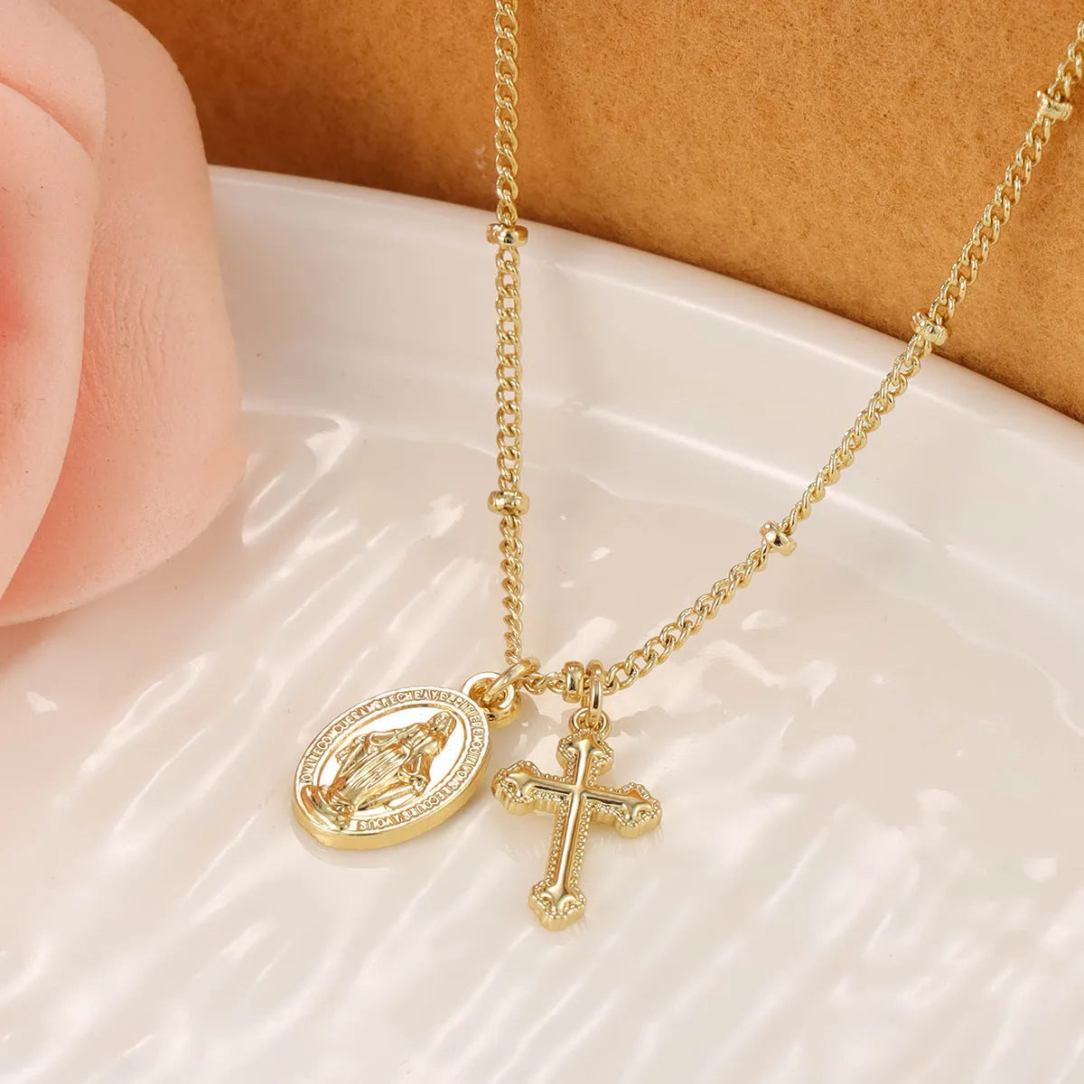 Gold-coloured geometric cross pendant necklace featuring the Virgin Mary, on a matching chain.