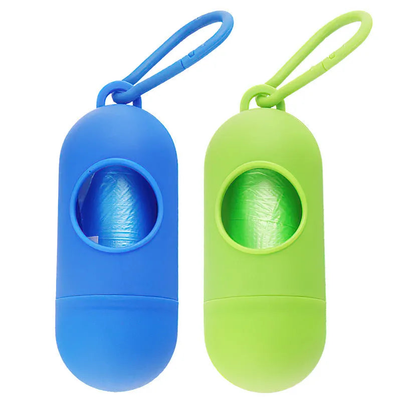 A compact black dog poop bag holder with a side hook and Velcro strap, shown next to a roll of waste bags.