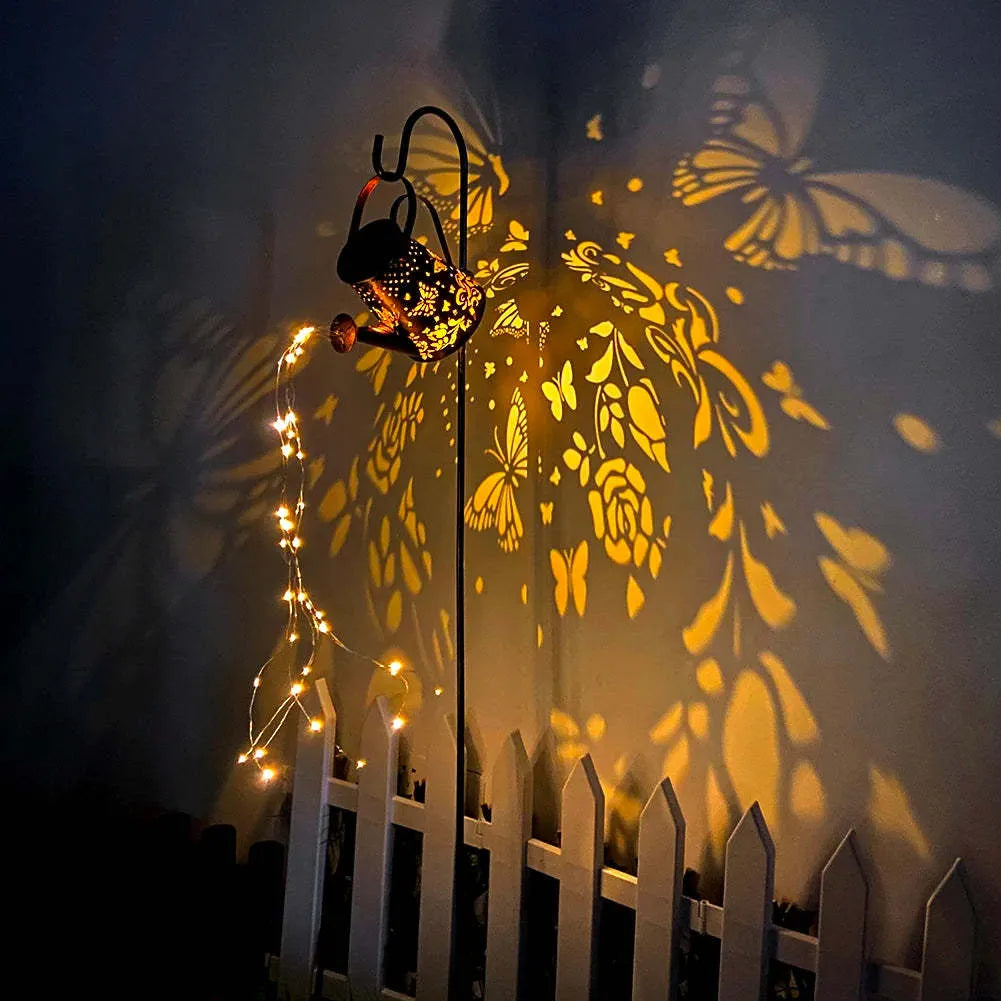 Tapered iron solar garden lantern with butterfly pattern emitting warm white light.