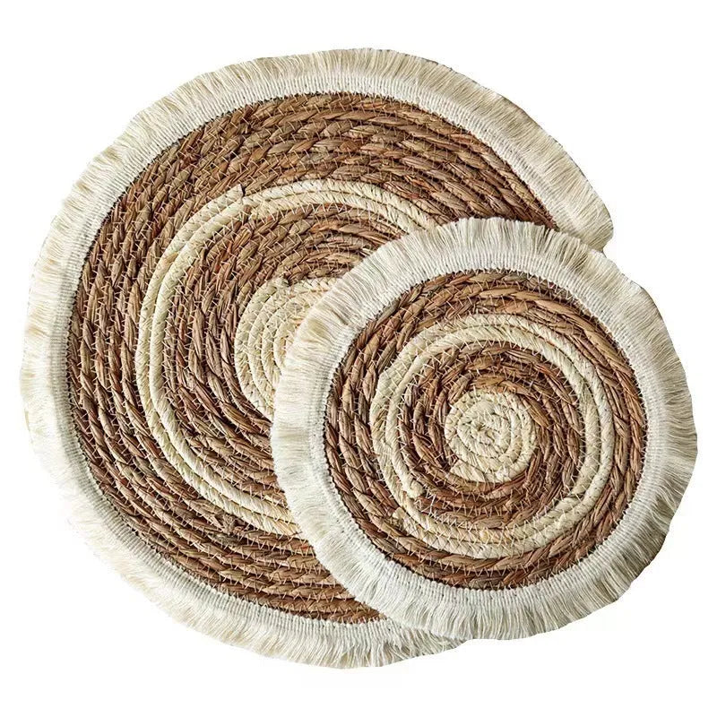 Round natural papyrus straw placemat with decorative tassels on a table
