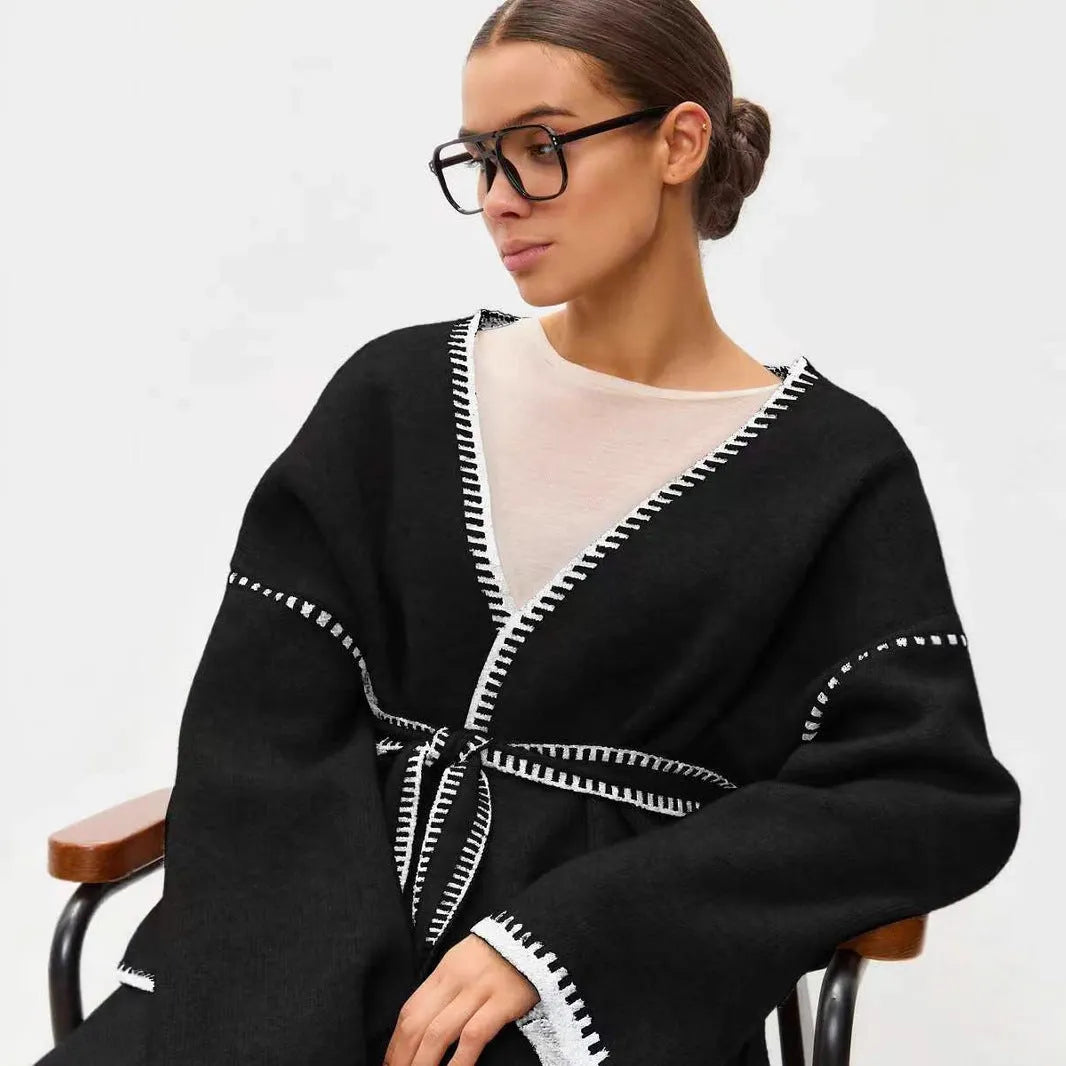 A loose, mid-length knitted cardigan with a front lace-up detail, shown in a camel colour.