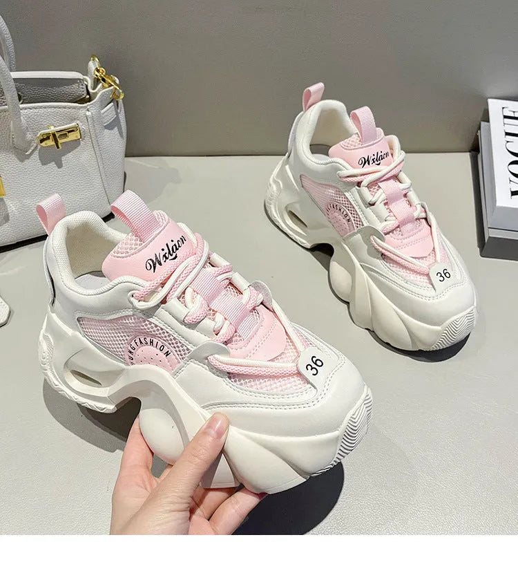 Women's pink casual sneakers with a cross strap, thick rubber sole, and mesh lining on a white background.