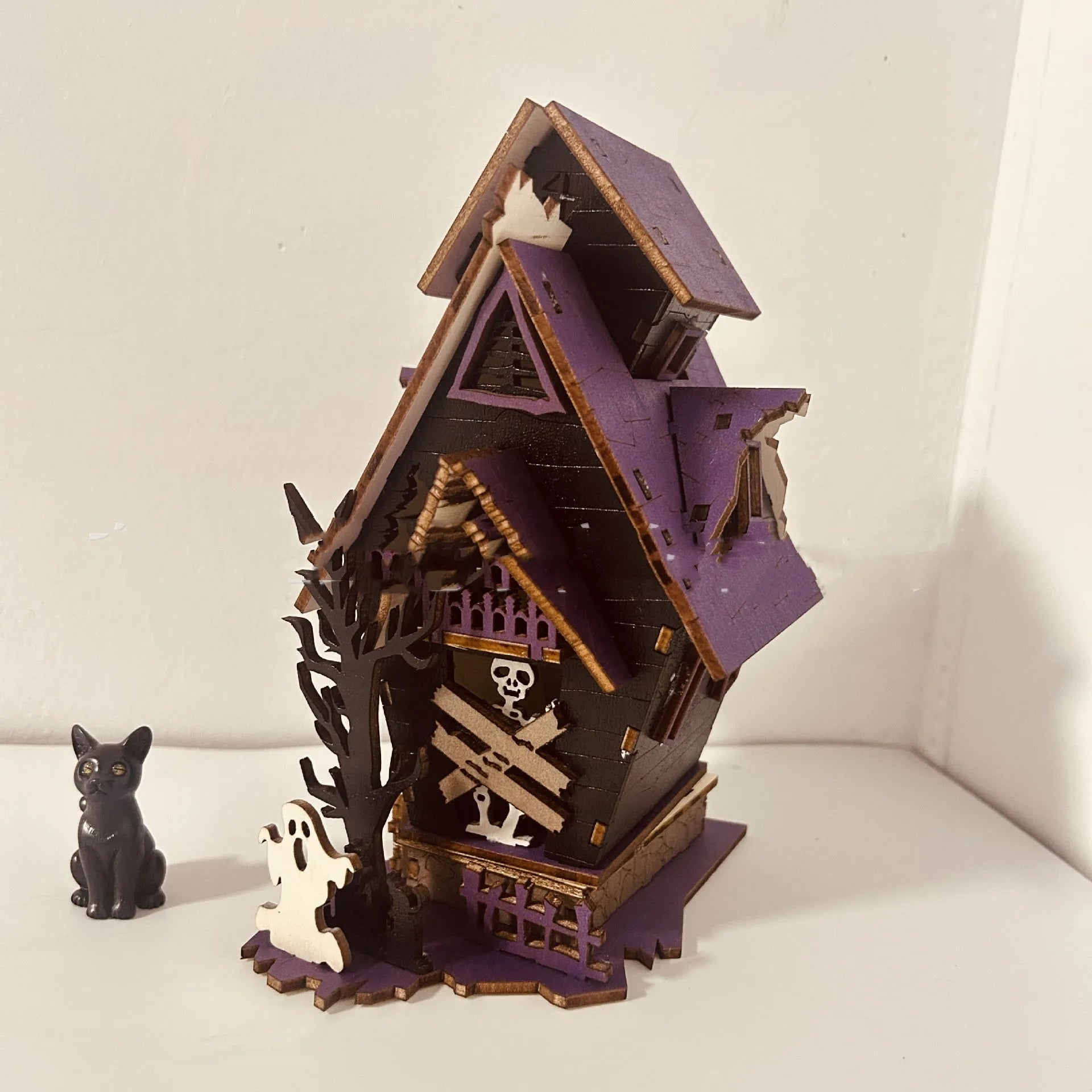 Unassembled DIY wooden haunted house Halloween decoration kit with glowing colour details.
