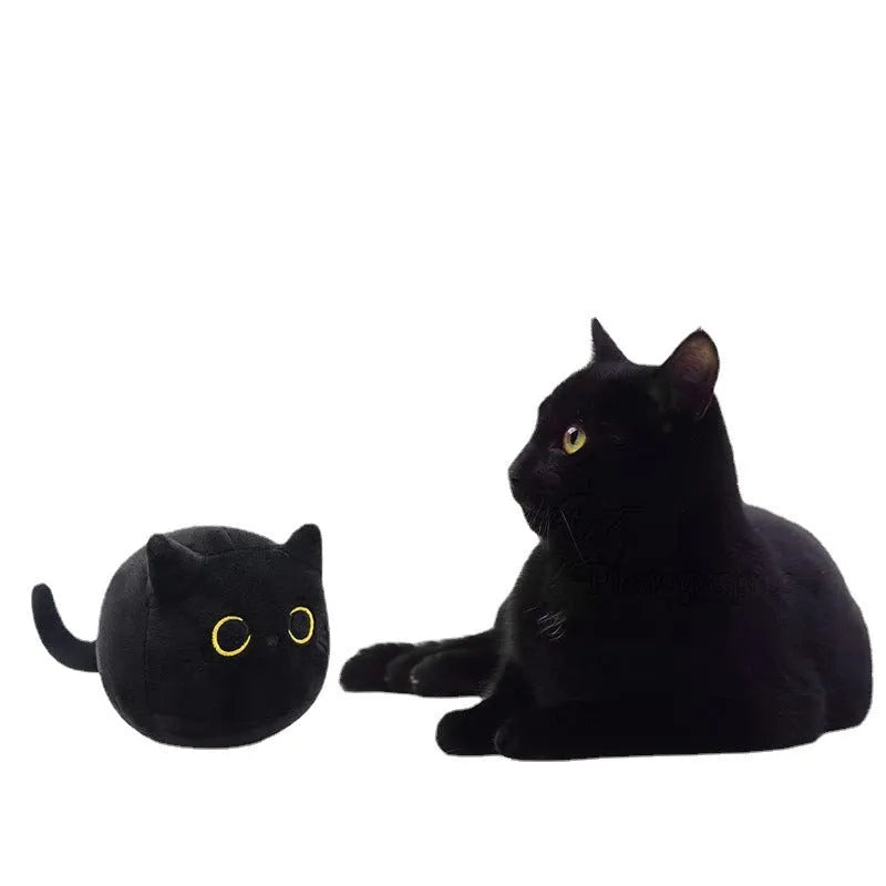 Black cat plush toy stuffed animal sitting as a soft pillow cushion on a sofa.