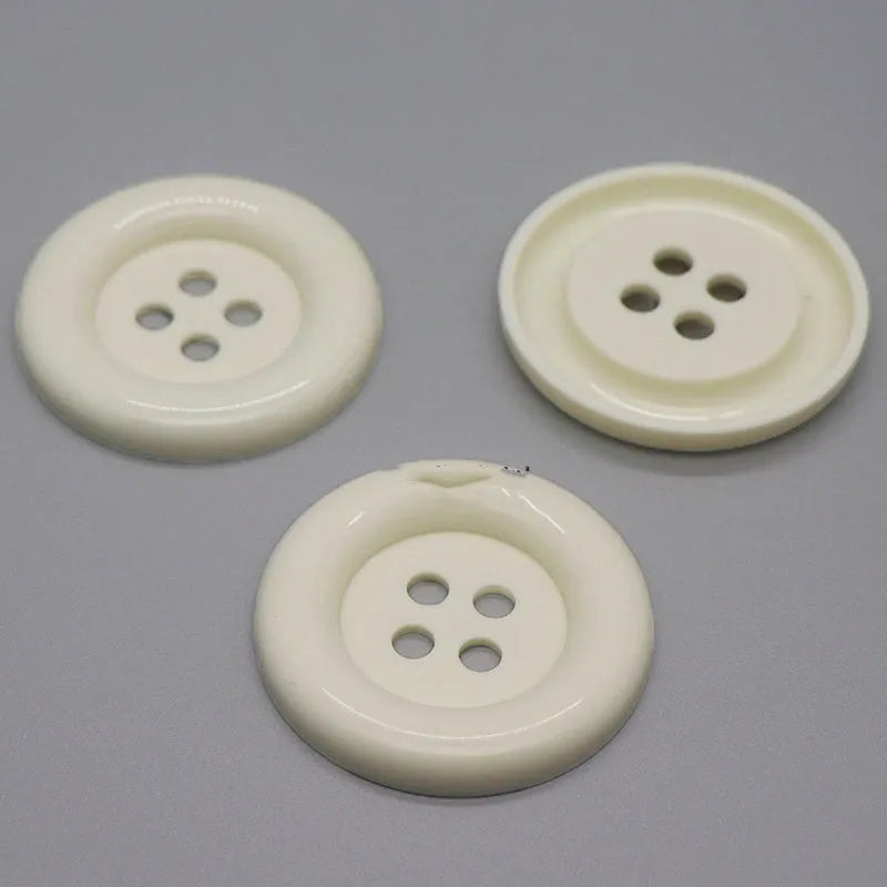 Assortment of oversized round plastic buttons in multiple colours with four stitching holes.