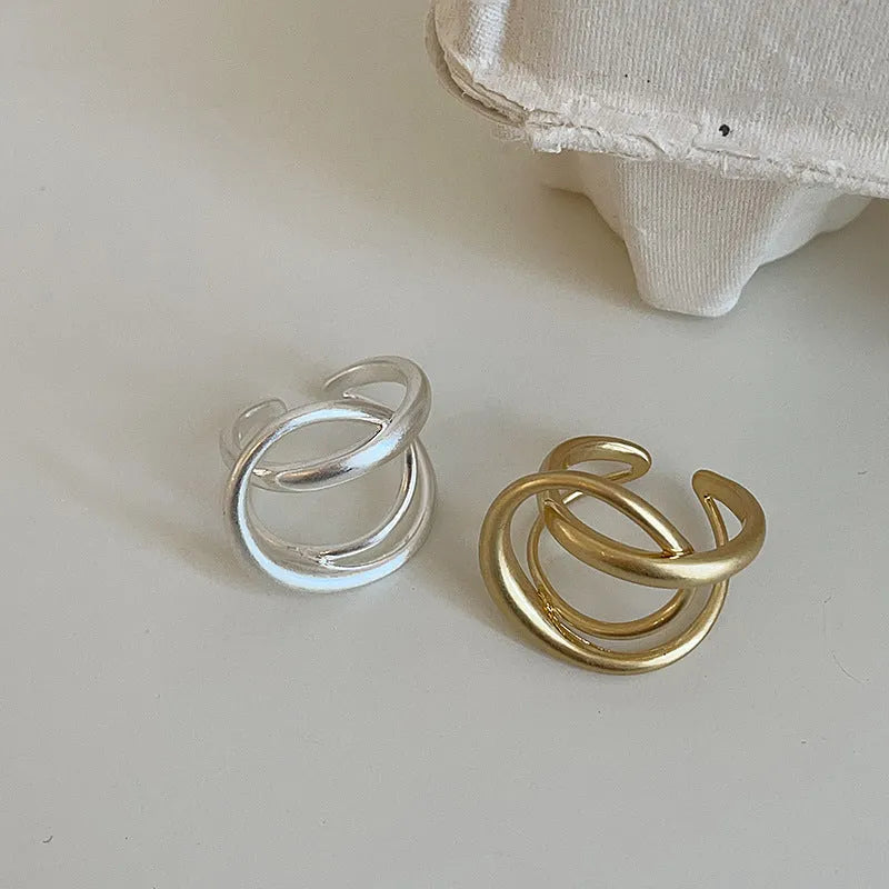 Geometric open ring with 3D interlaced matte metal design in gold or silver finish.