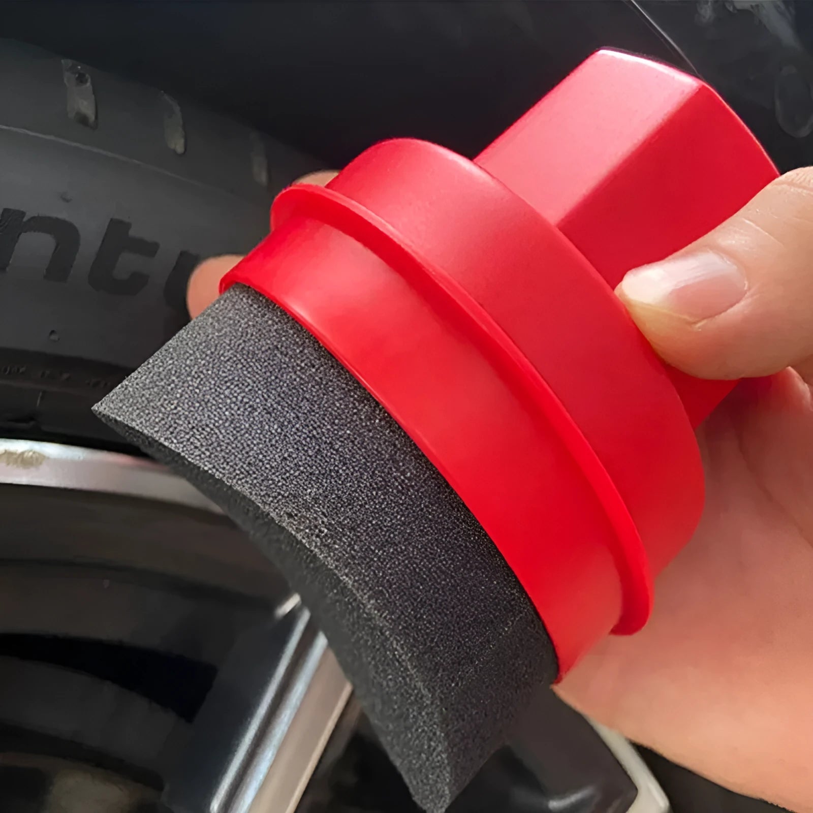 Black and red car tyre polishing sponge brushes with lids on a tyre sidewall