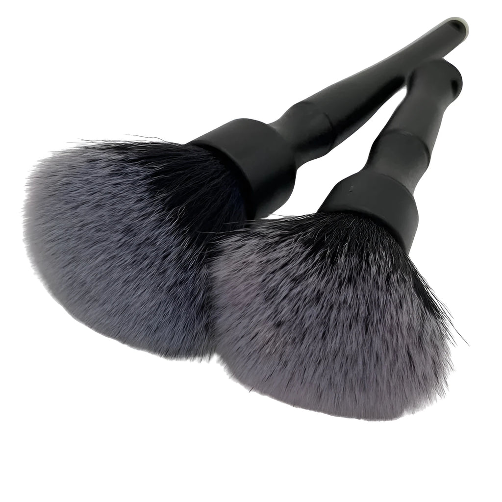 Black ultra-soft pig hair car detailing brush for interior cleaning on a car dashboard.