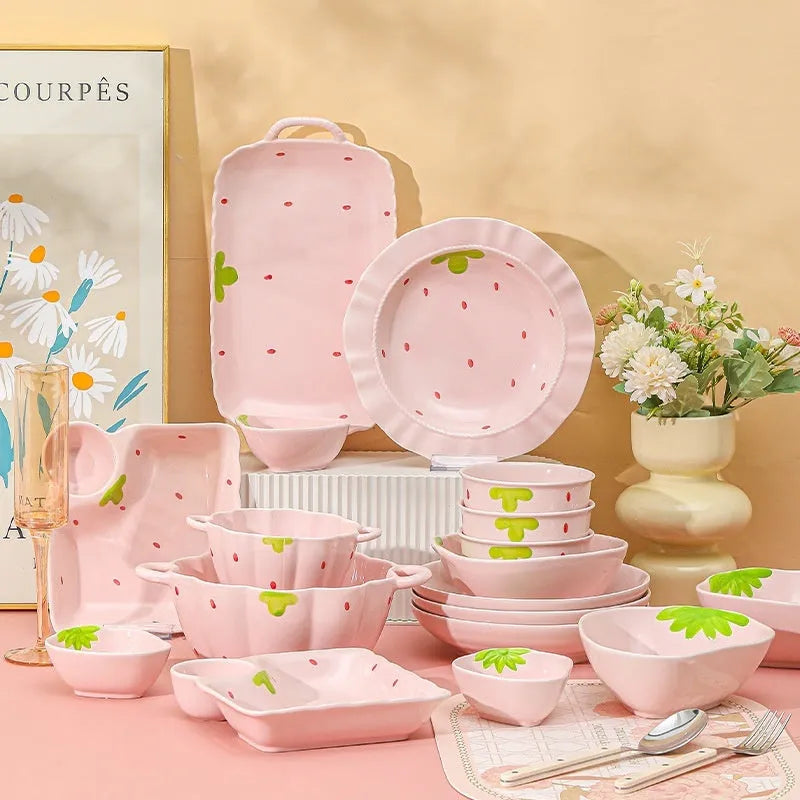 Cute strawberry pattern porcelain dinnerware set showing bowl, plate, and twist spoon on a table.