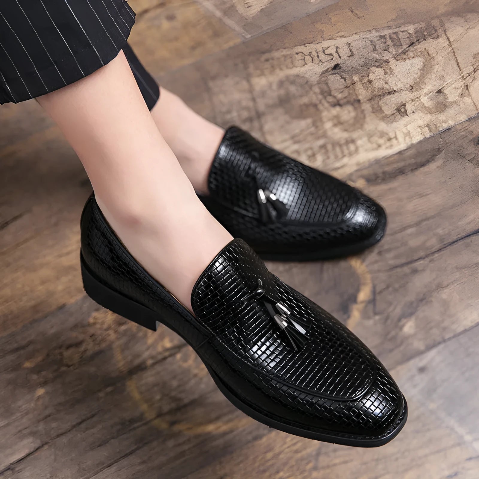Men's black pointed-toe slip on shoes with a tassel detail on the low-top PU upper.