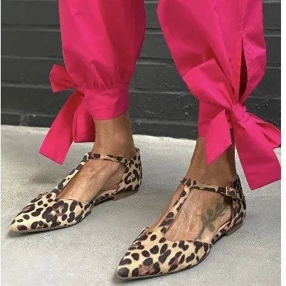 Leopard print women's pumps with a pointed toe, cross straps, and a low chunky heel on a rubber sole.