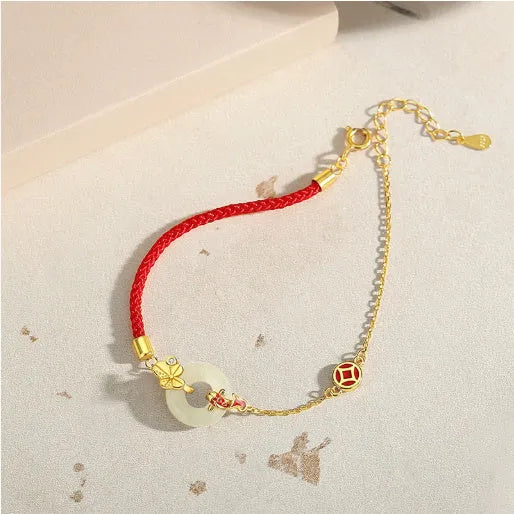 Women's silver bracelet with gold peace buckle and koi fish charm on a red rope.