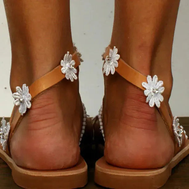 Brown women's Roman sandals with flower detail and herringbone toe design on flat rubber sole