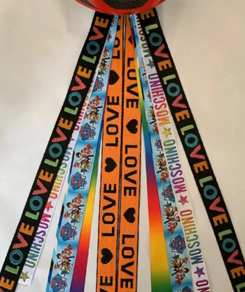 Colourful fabric helmet streamers for children's roller skating and ski helmets, shown in apricot, red, and grey.