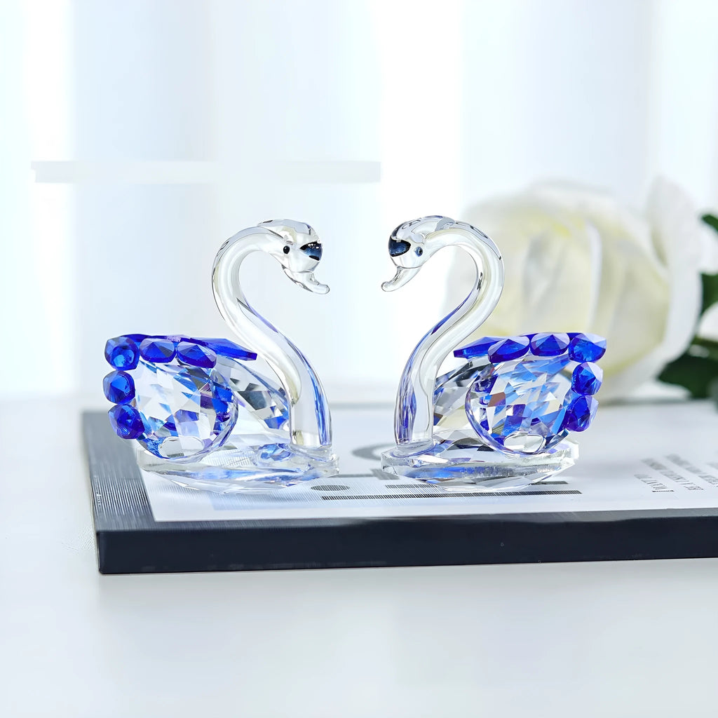 White crystal swan decoration on a desktop in solid head and empty tube styles.