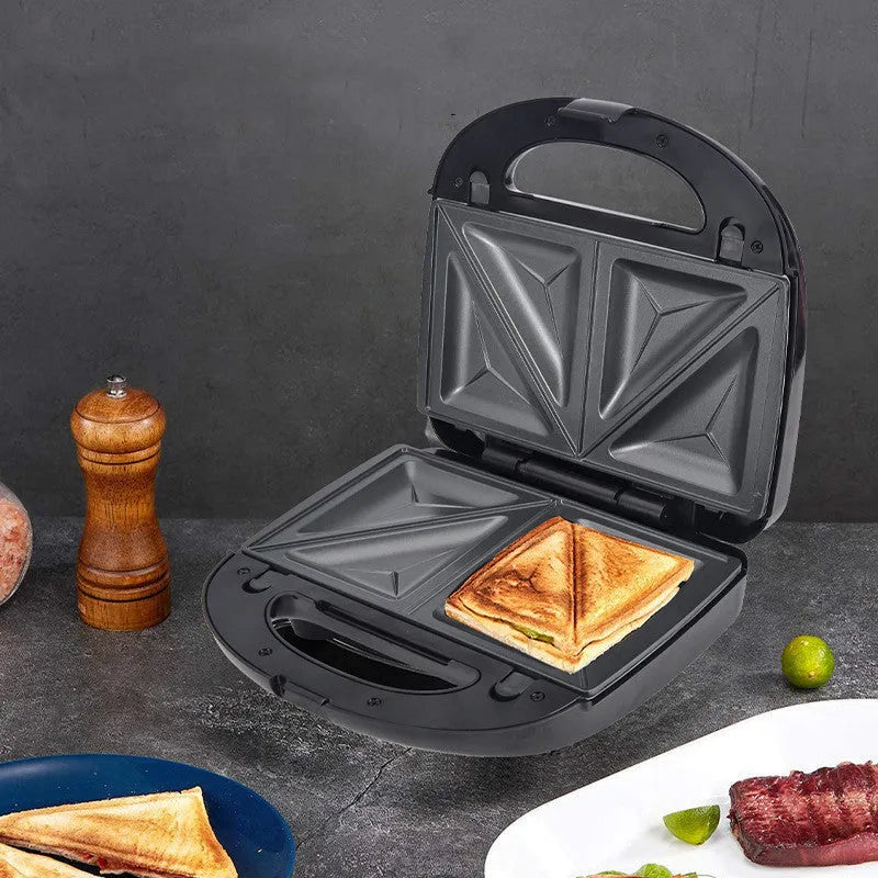 Black double-sided electric sandwich pan with stainless steel lid on a kitchen counter.