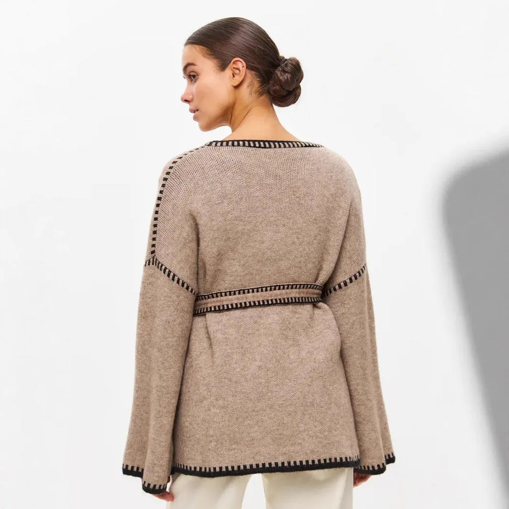 A loose, mid-length knitted cardigan with a front lace-up detail, shown in a camel colour.