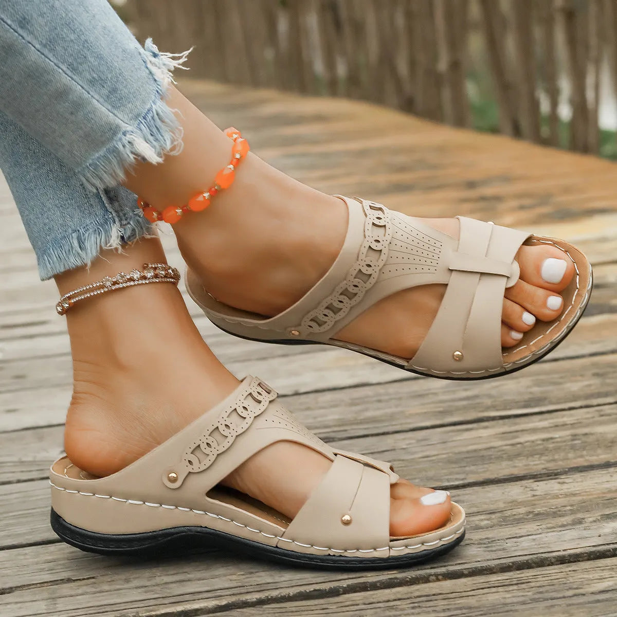Women's beige Roman style slippers with a slope heel and fish mouth toe holder on a rubber sole.