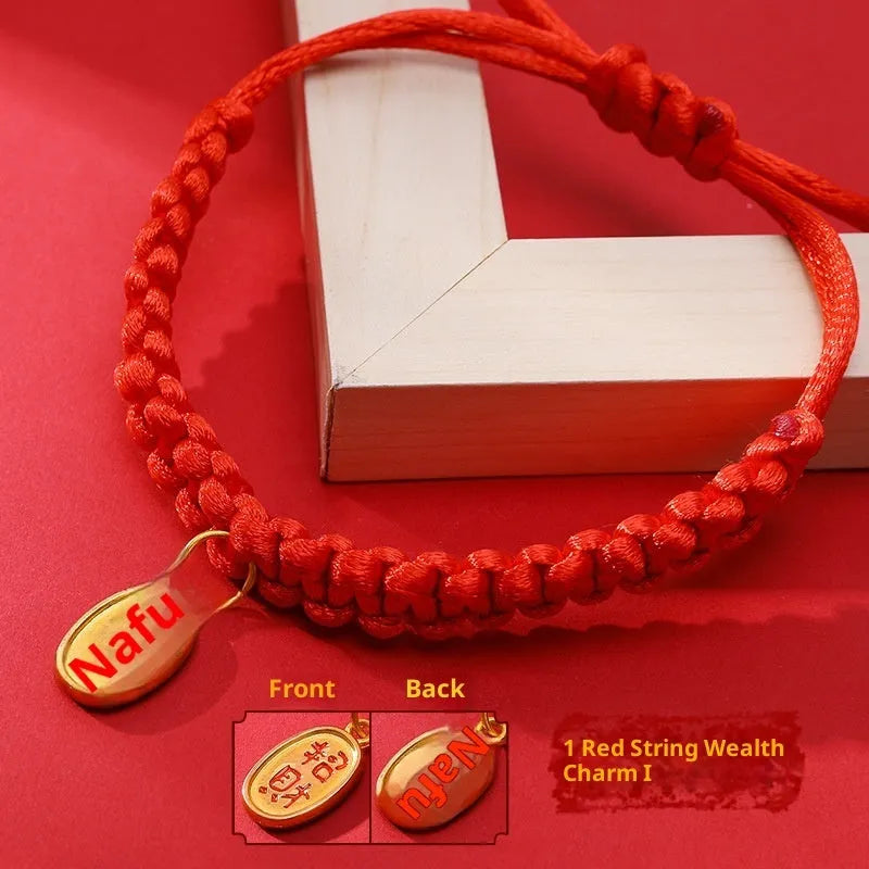 Adjustable hand-woven red rope pet collar with alloy lucky charm on wooden surface