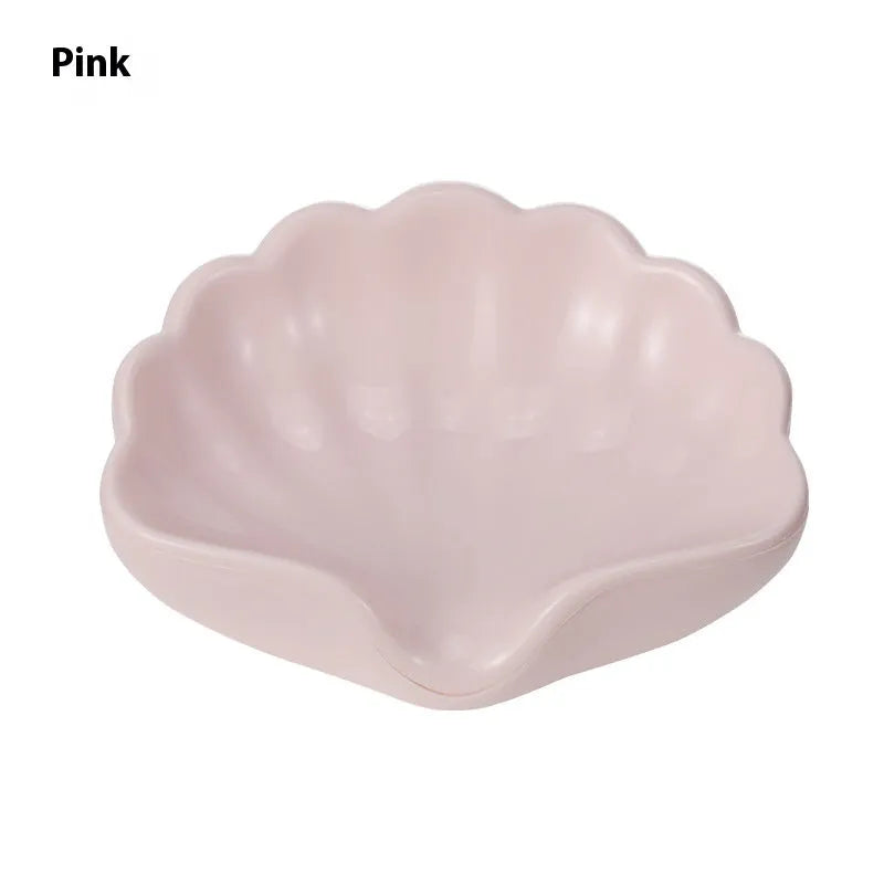 White or pink plastic shell-shaped soap dish for bathroom use.