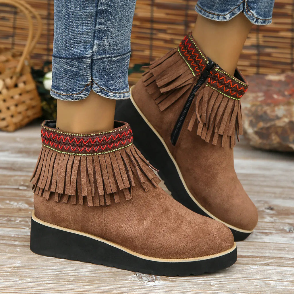 Women's suede ankle boots with a wedge heel, side zipper, tassel detail, and thick rubber sole.
