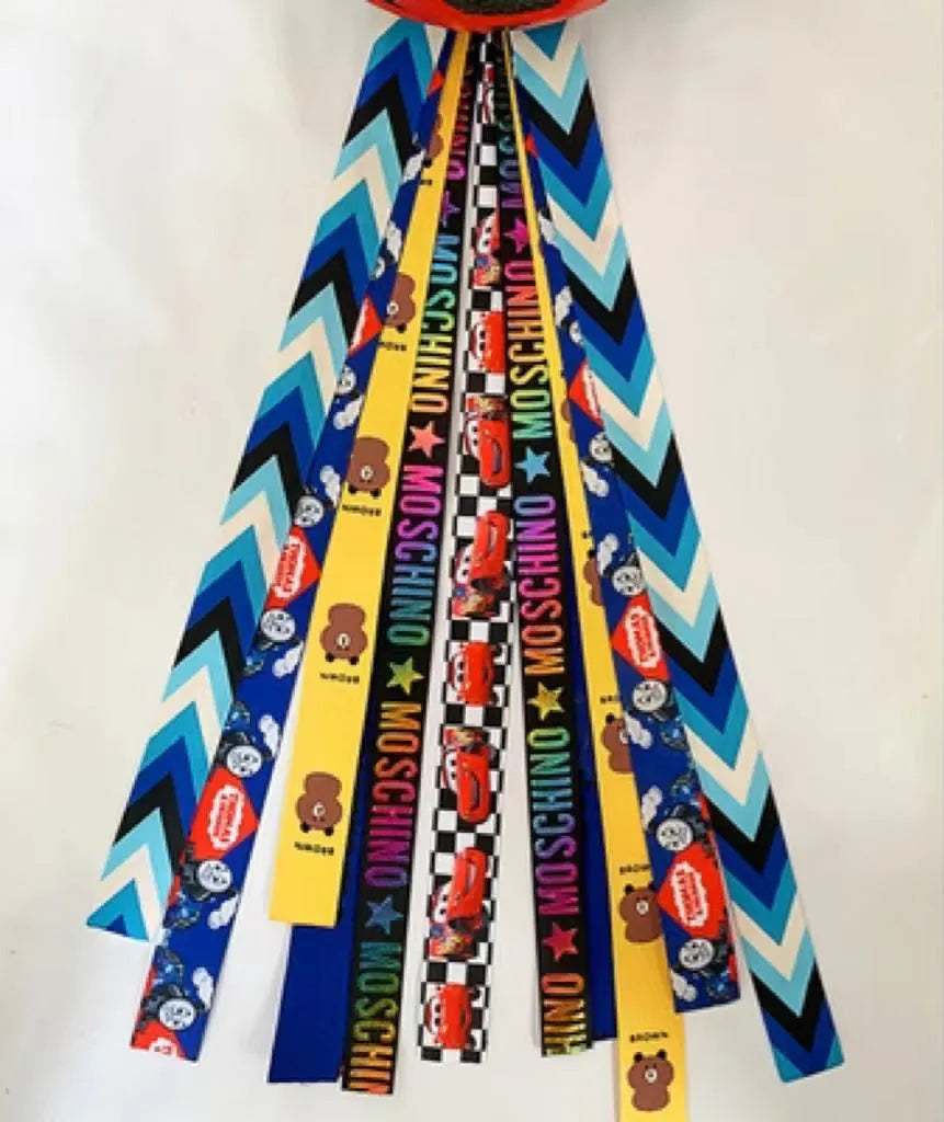 Colourful fabric helmet streamers for children's roller skating and ski helmets, shown in apricot, red, and grey.