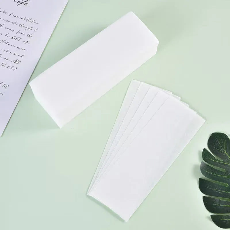 Pack of soft non-woven fabric hair removal wax paper strips on a pink background