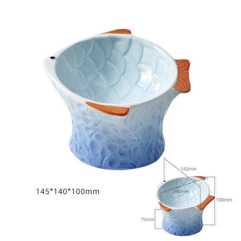 Blue fish-shaped ceramic cat feeder bowl with shallow tilt angle and non-slip base on a wooden surface.