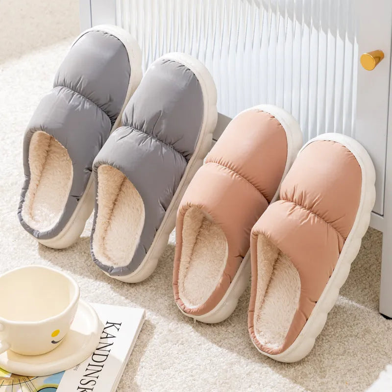 Pair of thick-soled indoor slippers in blue with a wrapped toe, low heel, and artificial plush lining.
