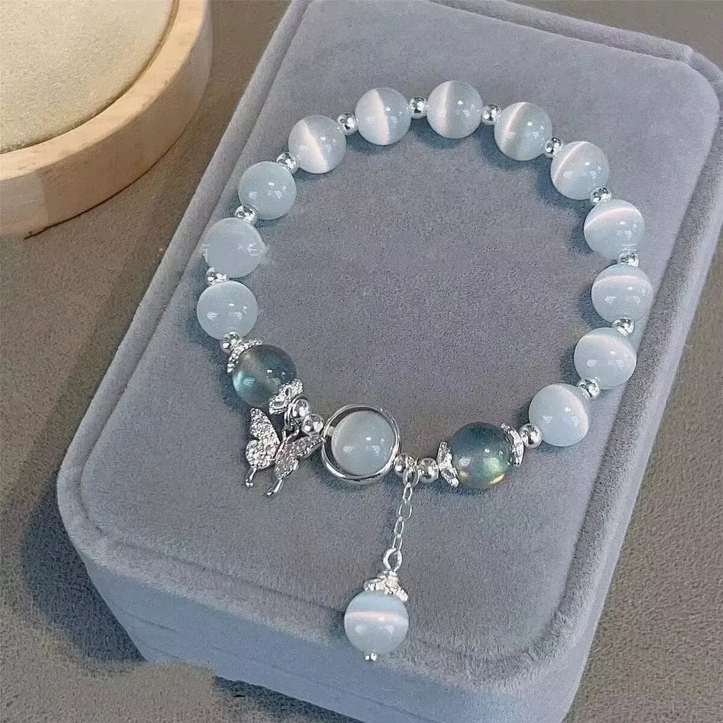 Close-up of a drop-shaped glass butterfly bracelet with round coloured beads on a wrist.