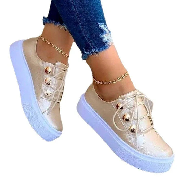 Women's white lace-up flats sneakers with decorative silver rivets on the sides.