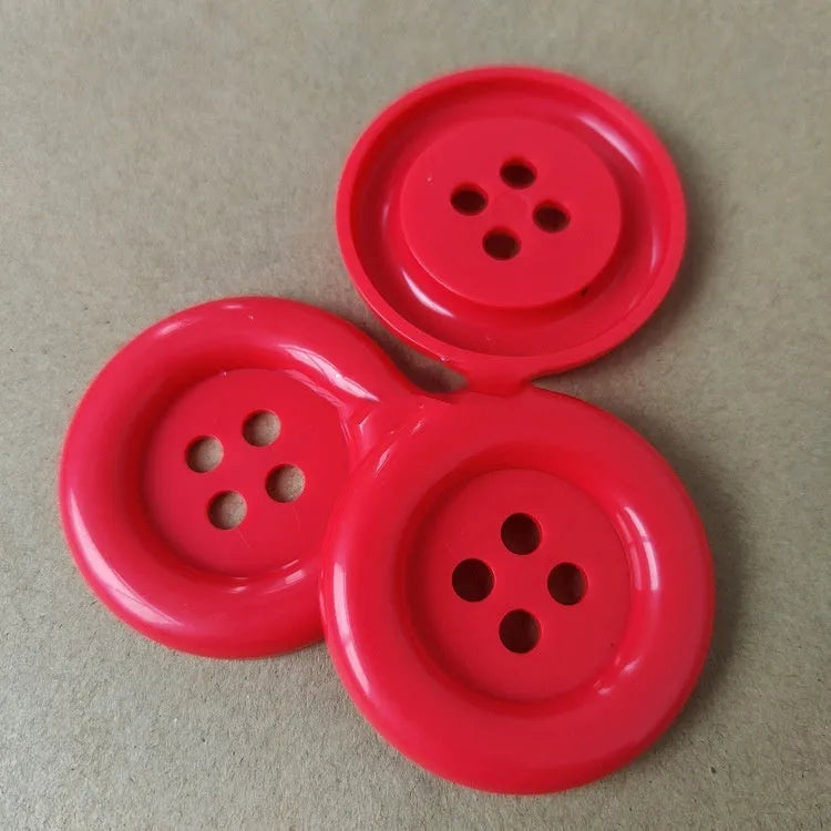 Assortment of oversized round plastic buttons in multiple colours with four stitching holes.