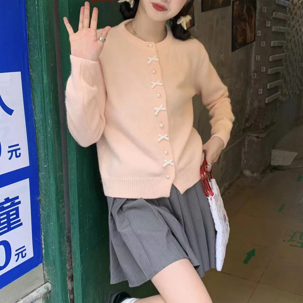 Women's solid colour cardigan sweater with bow-shaped pearl buttons on the front.