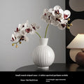 White ceramic ball vase with blue stripes on wooden table